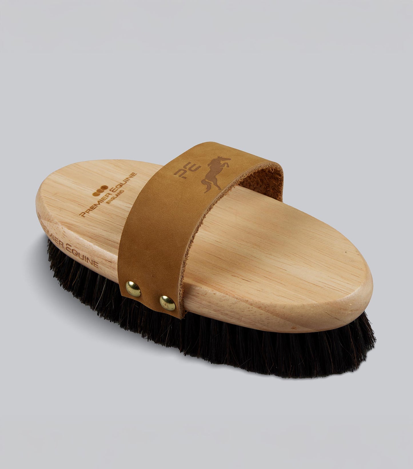 Wooden brush with a brown leather strap on a gray background