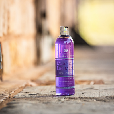 Purple bottle of lavender liniment on a wooden surface with a blurred background