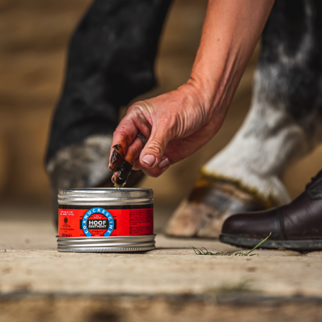 Person opening a can of Hoof Care product for a horse