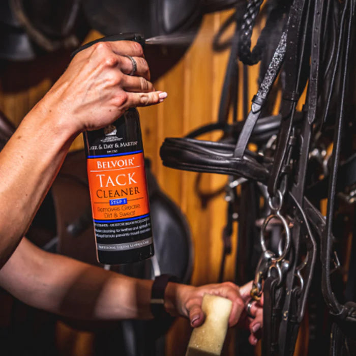Person cleaning horse tack with Belvoir Tack Cleaner in a stable setting