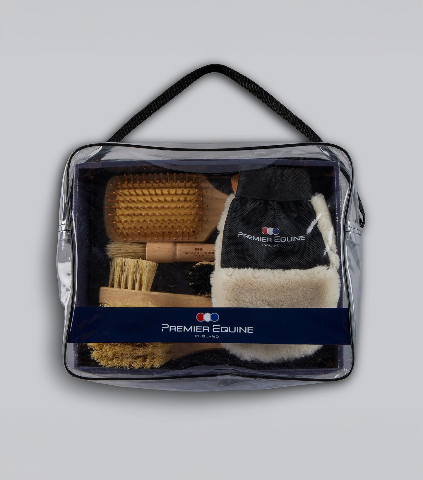 Clear travel bag with horse grooming tools and Premier Equine branding on a light gray background
