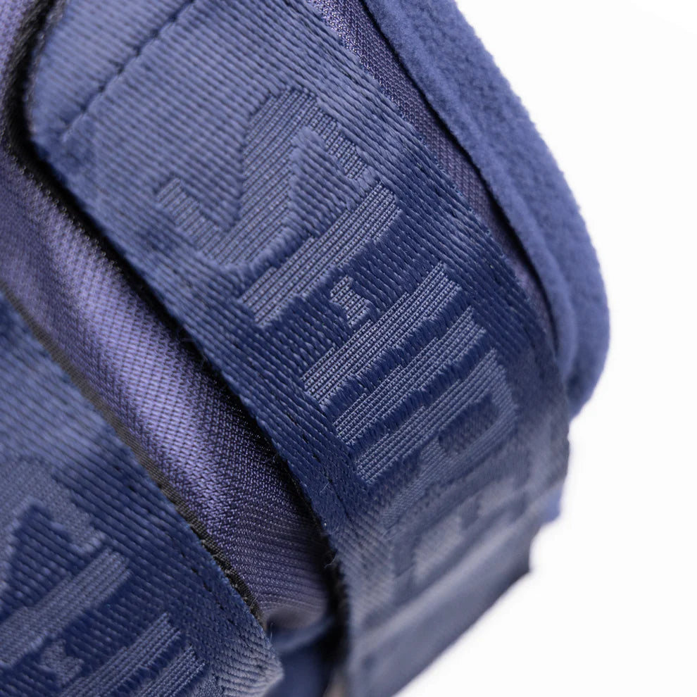 Close-up of a navy blue fly mask closure with brand logo on a white background