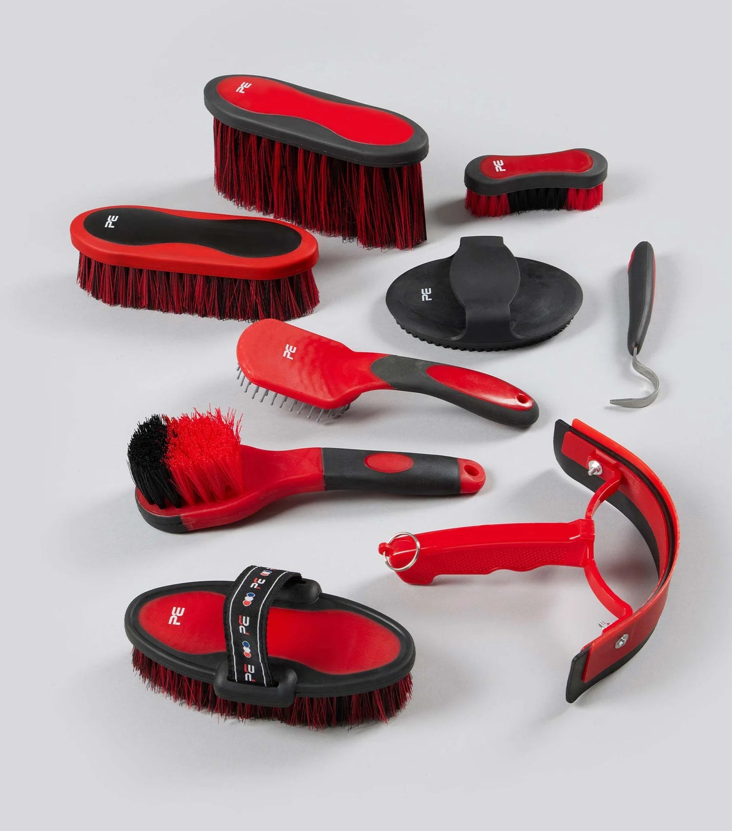 Set of red and black grooming brushes and tools on a white background