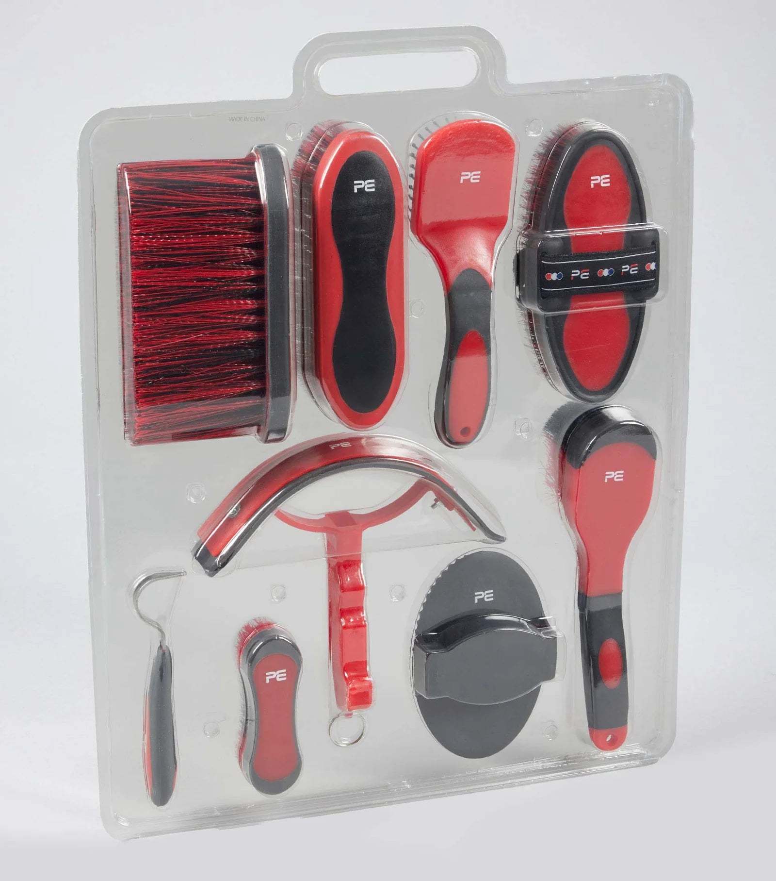 Set of red grooming tools with black bristles in clear packaging on a white background