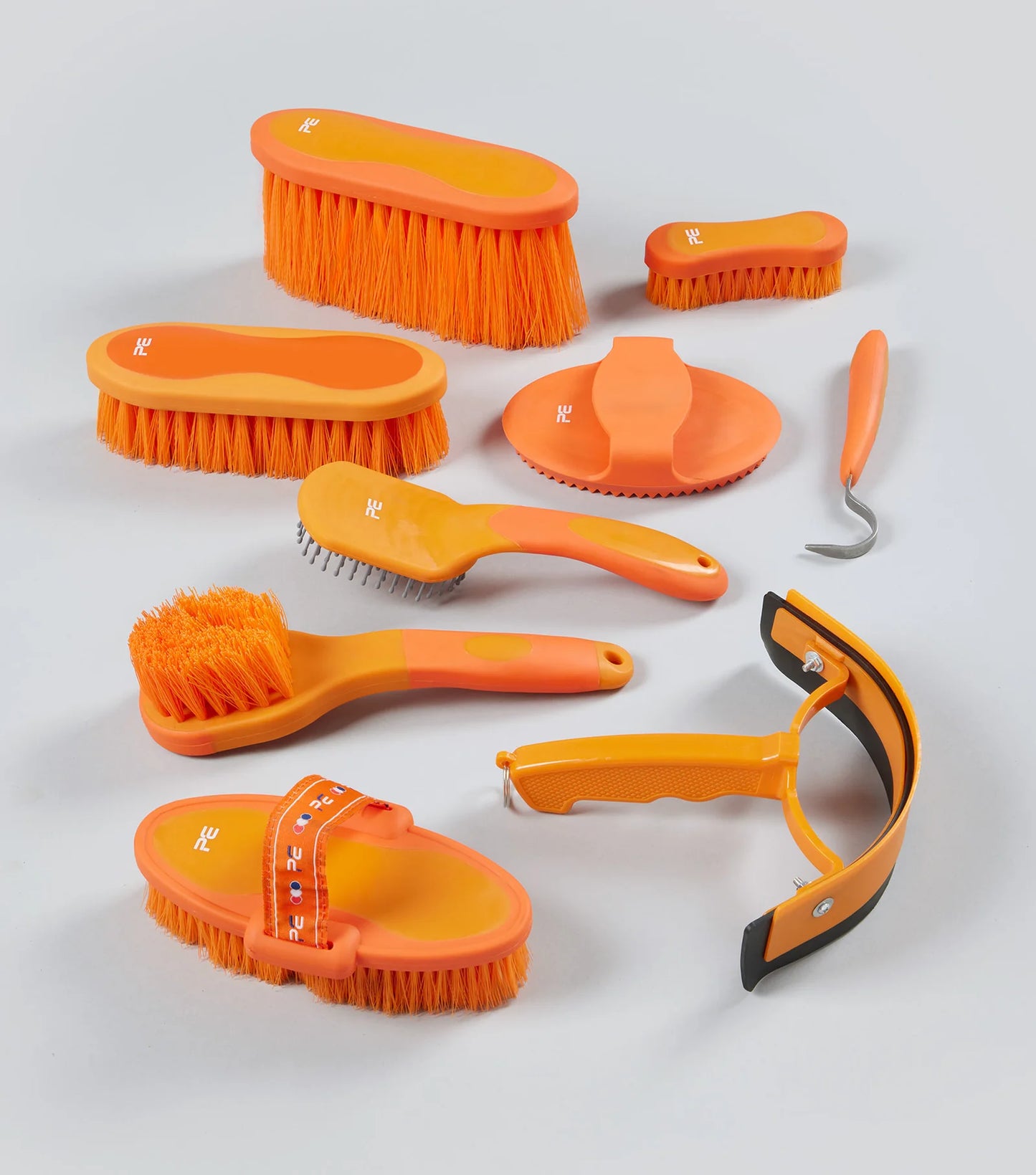 Set of orange grooming brushes and tools on a light gray background