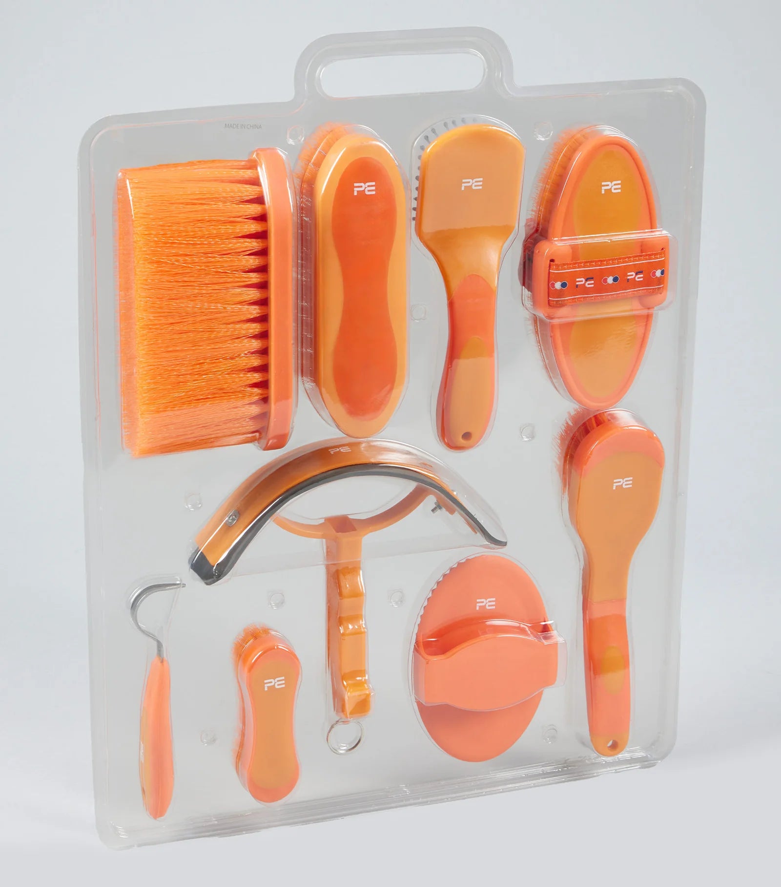 Set of orange grooming tools in packaging on a light gray background