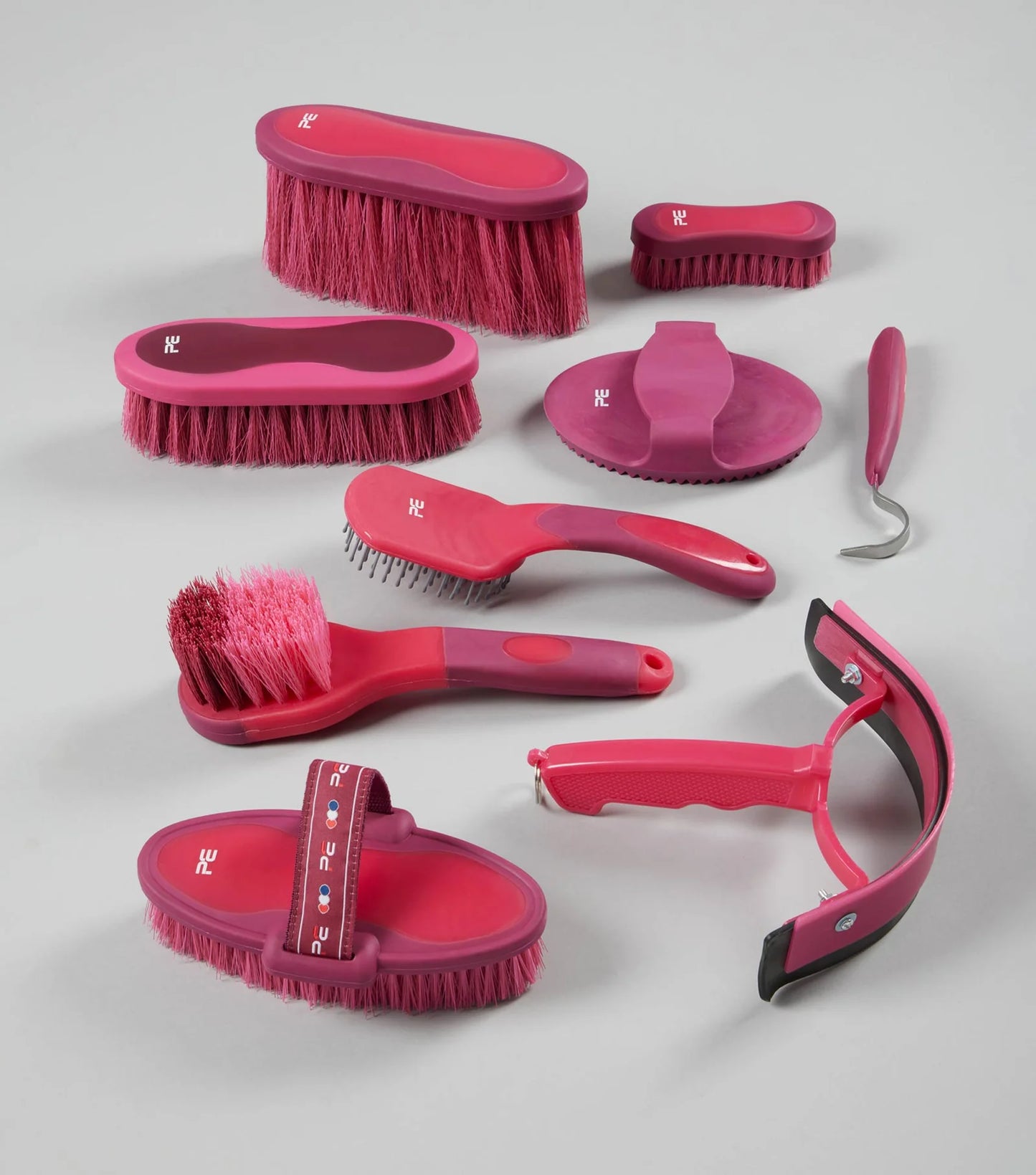 Set of pink grooming brushes and tools on a gray background