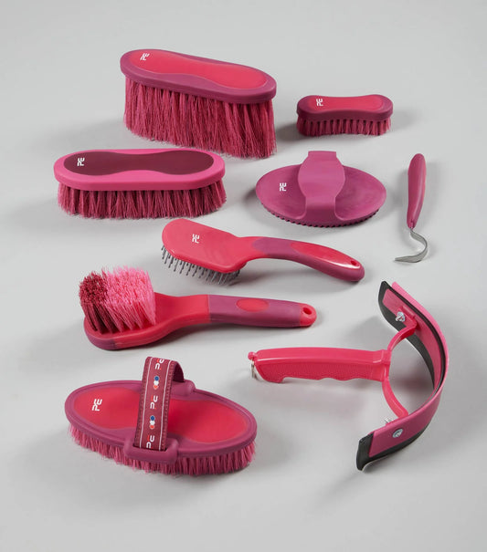 Set of pink grooming brushes and tools on a gray background