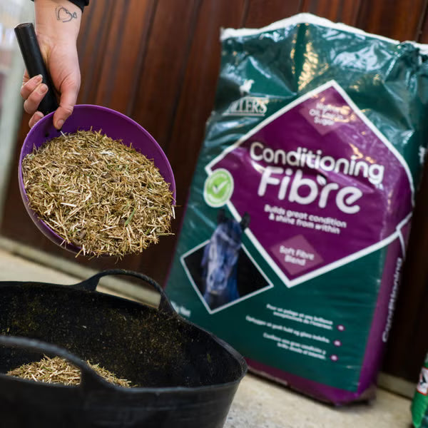 Person holding a scoop next to a bag of Spillers Conditioning Fibre pet food.