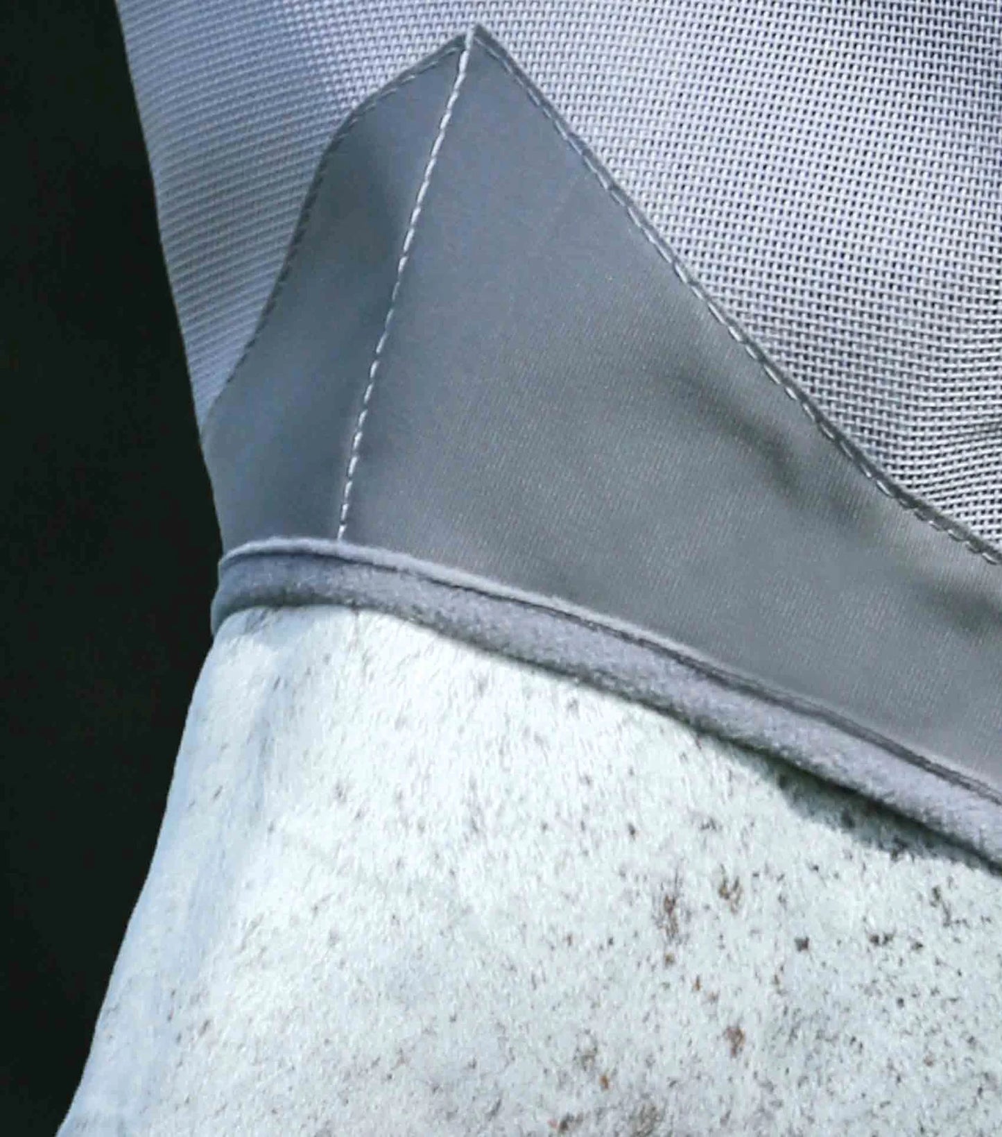 Close-up of a gray fabric with stitching detail on a textured surface.