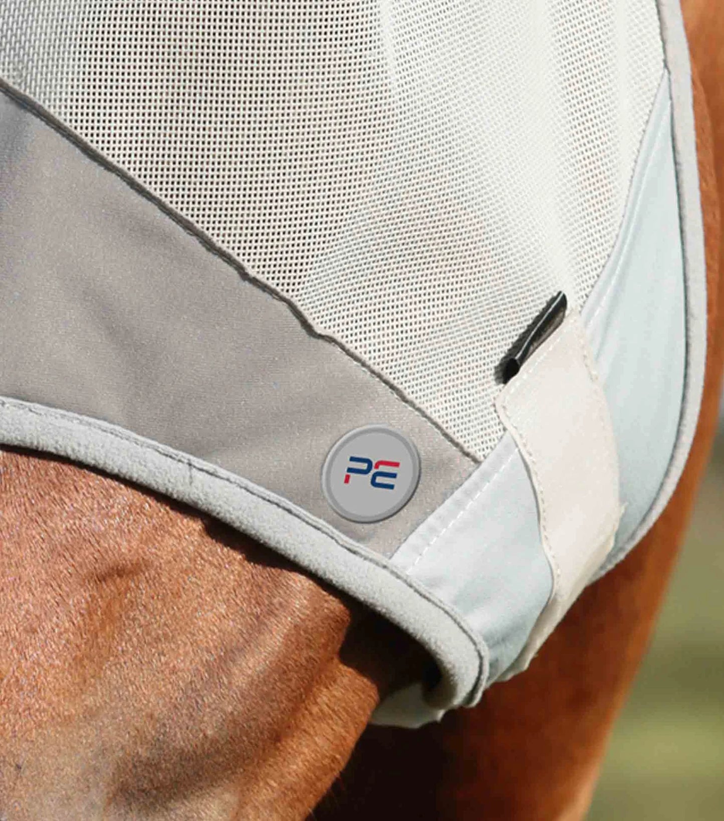 Close-up of a horse wearing a protective fly mask with a visible brand logo.